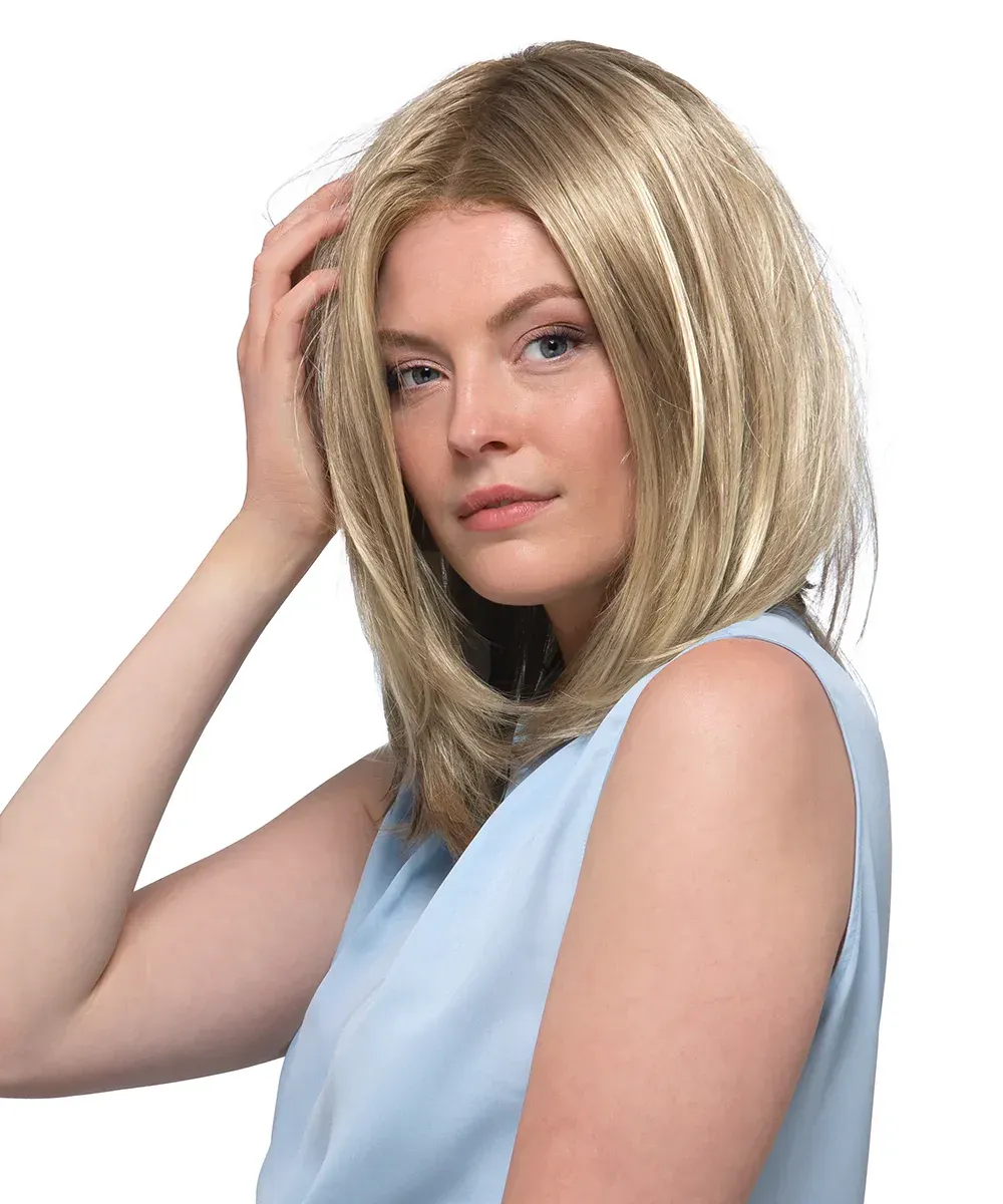 A woman wearing a blonde wig and a blue shirt is touching her hair.