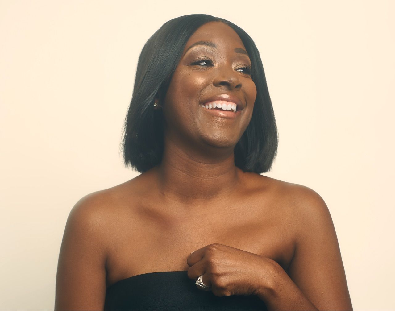 A woman is wearing a black strapless top and smiling.
