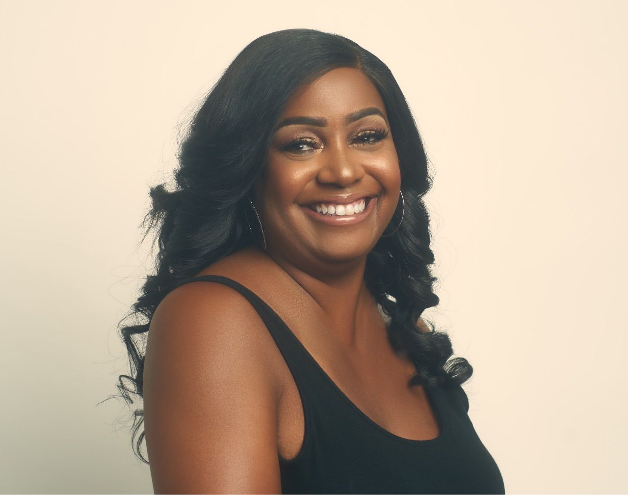 A woman in a black tank top is smiling for the camera