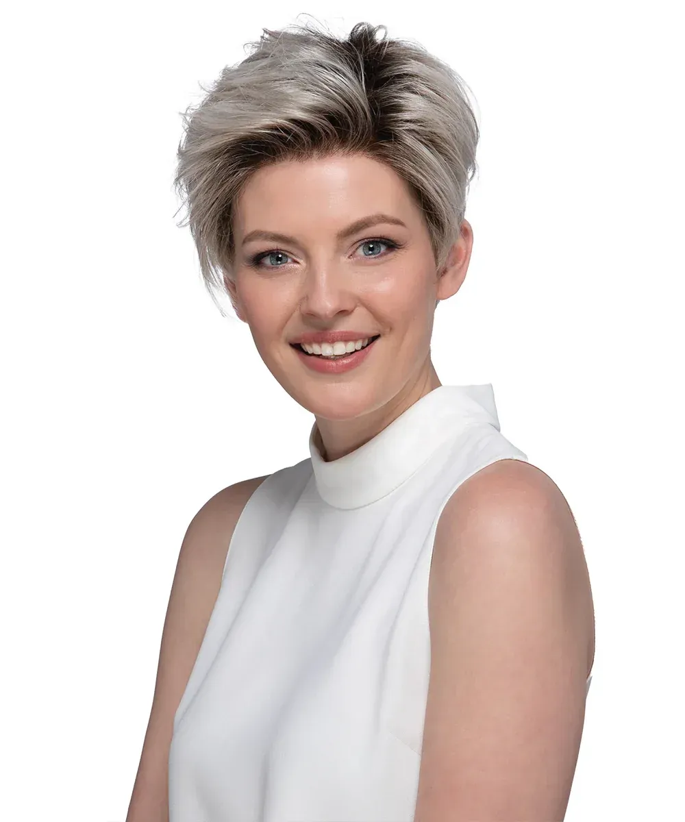 Woman with short, layered blonde wig smiles; wearing a white sleeveless top.