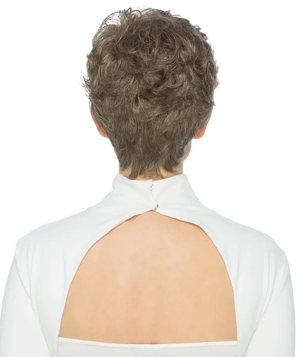 Woman with short, layered, gray wig, smiling, wearing a white turtleneck.