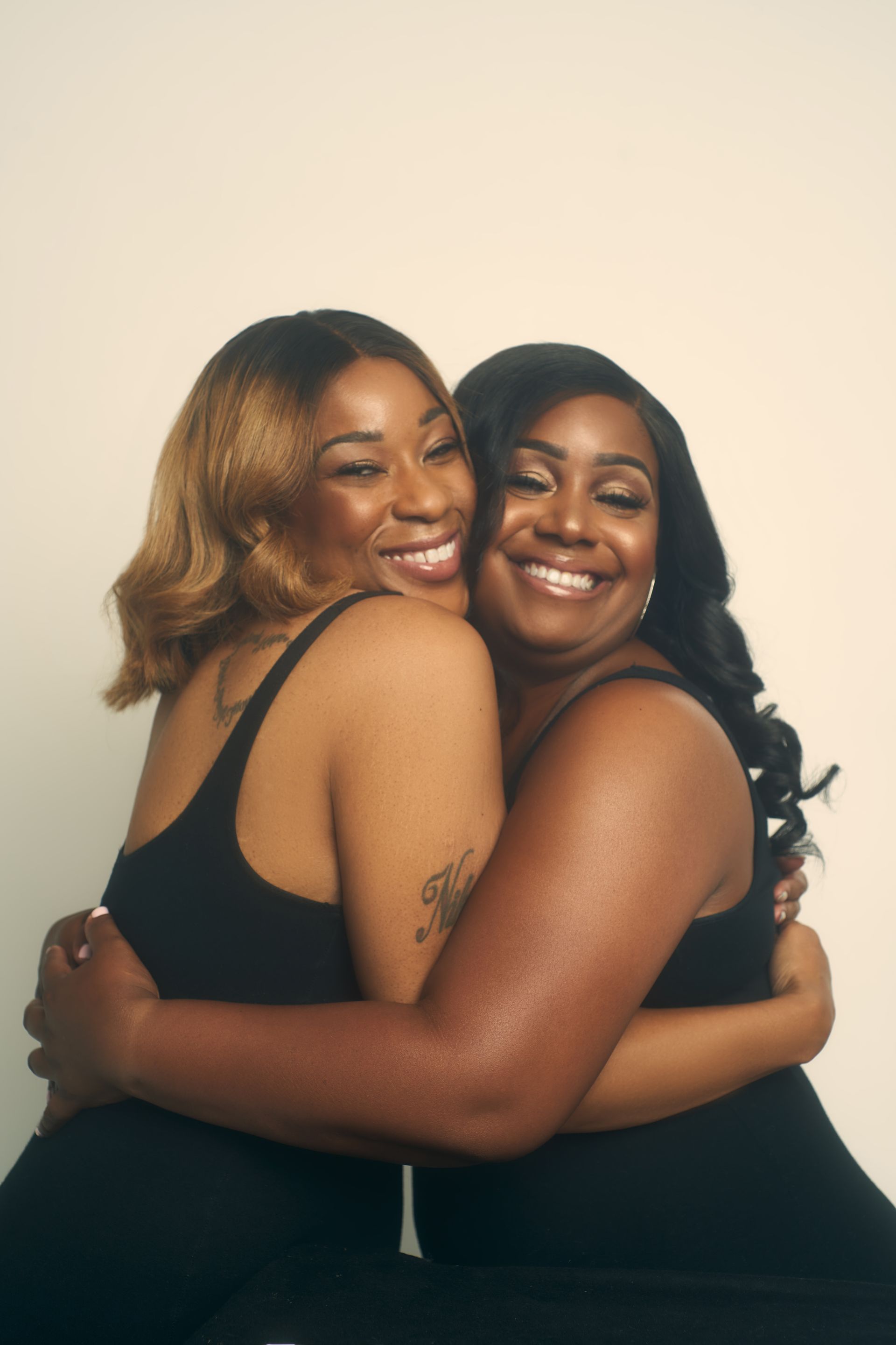 Two women are hugging each other and smiling for the camera.