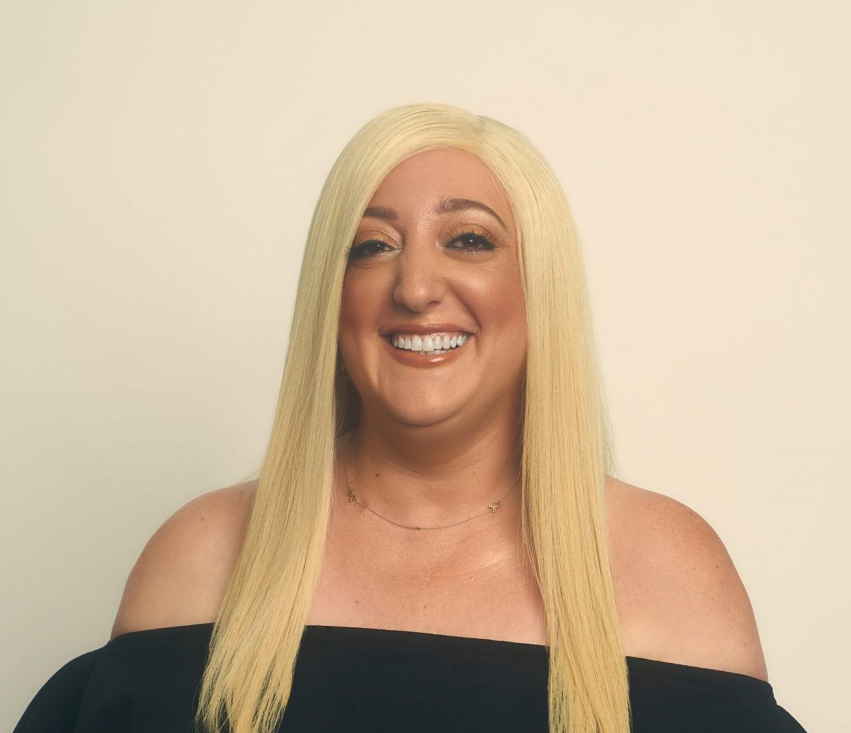 A woman with blonde hair is smiling and wearing a black top
