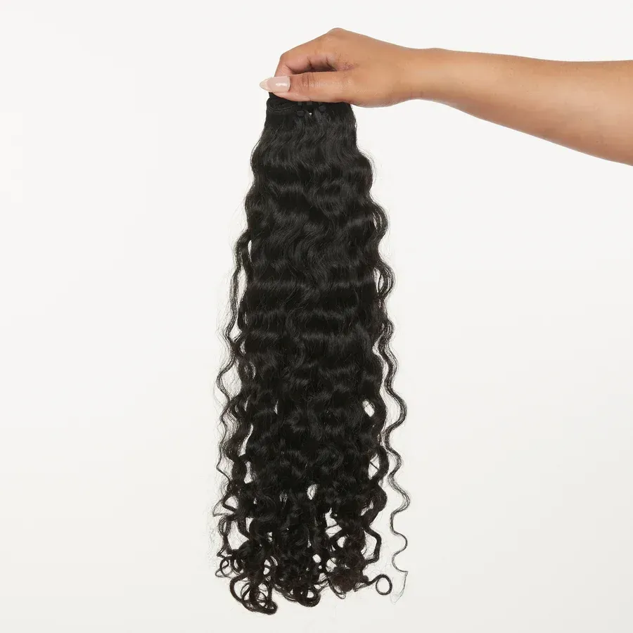A person is holding a piece of curly hair in their hand.