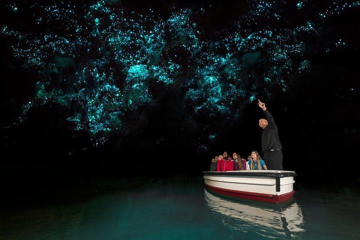 A group of people are riding in a boat in a cave at night.
