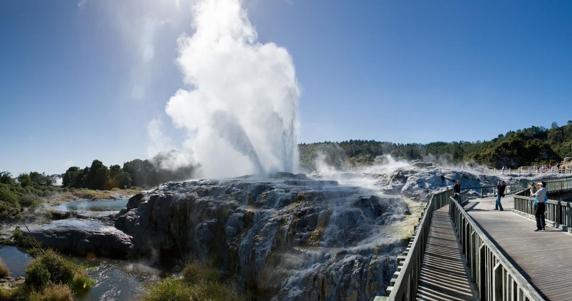 A bridge leading to a waterfall with smoke coming out of it.