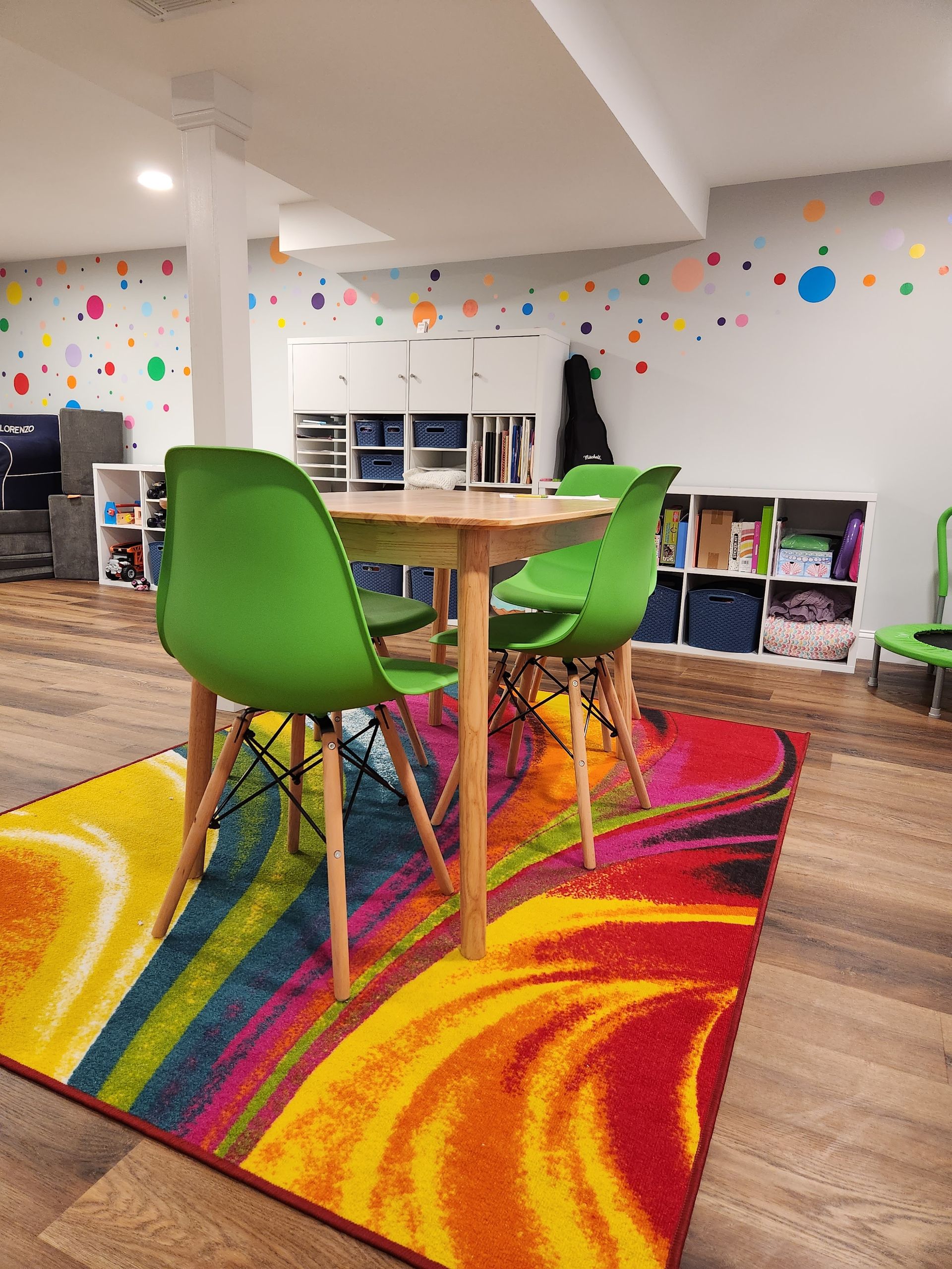 A room with a table and chairs and a colorful rug.