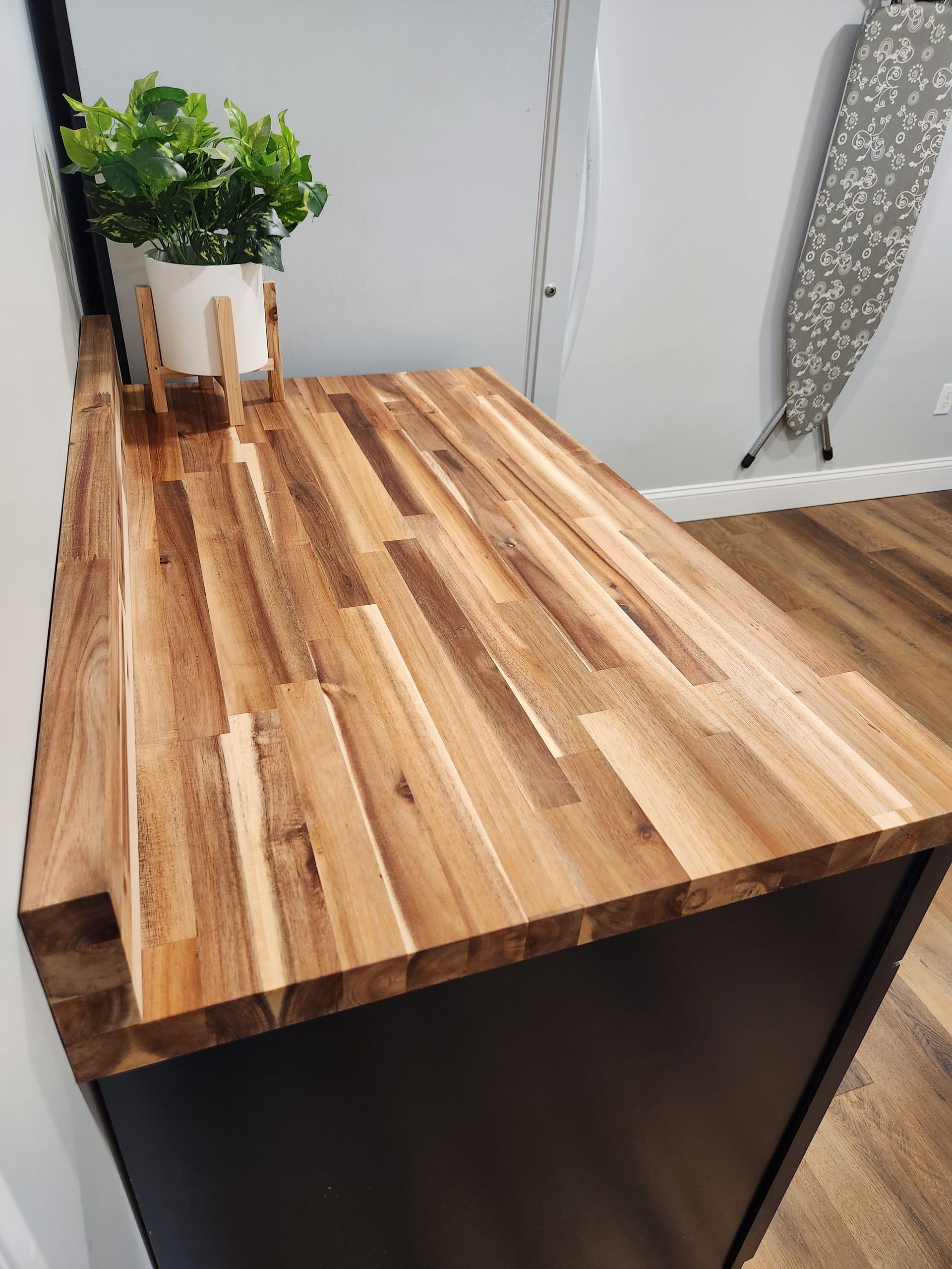 A wooden counter top with a plant on top of it in a laundry room.