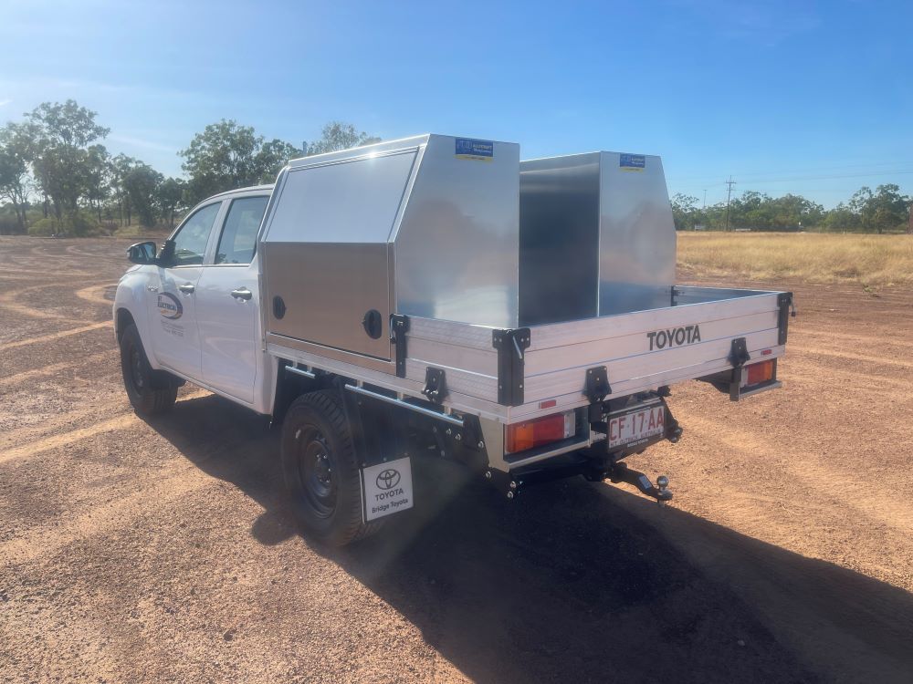 A White Toyota Truck With a Canopy on the Back is Parked in a Dirt Field — Allycraft Modifications in Berrimah, NT