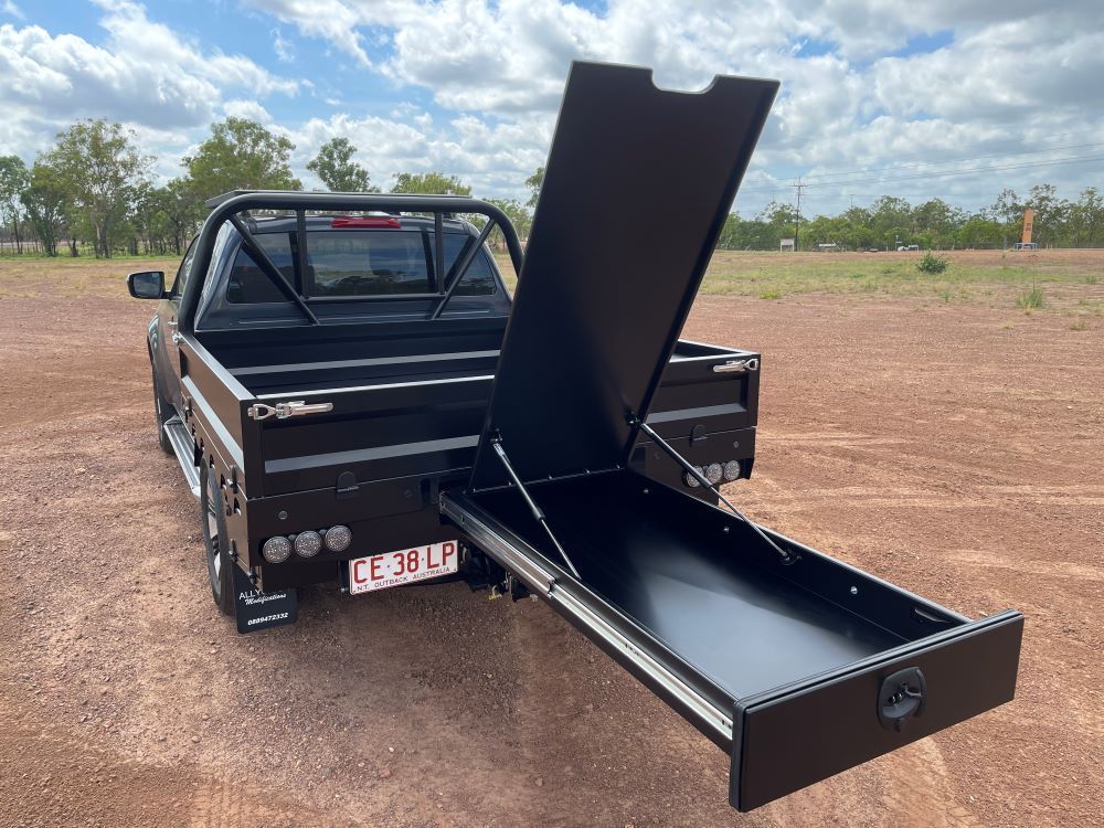 A Black Truck With the Ute Tray Open is Parked in a Dirt Field — Allycraft Modifications in Berrimah, NT