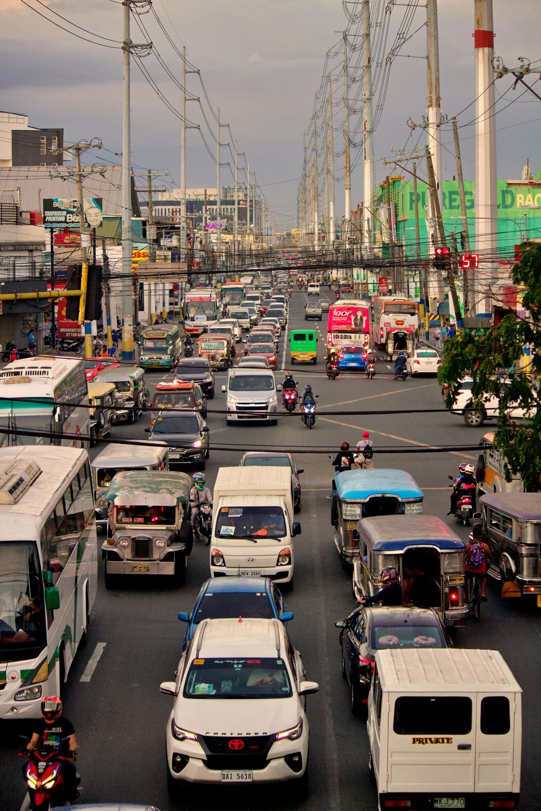 A congested city street in the Philippines filled with jeepneys, cars, and motorcycles during the daytime.