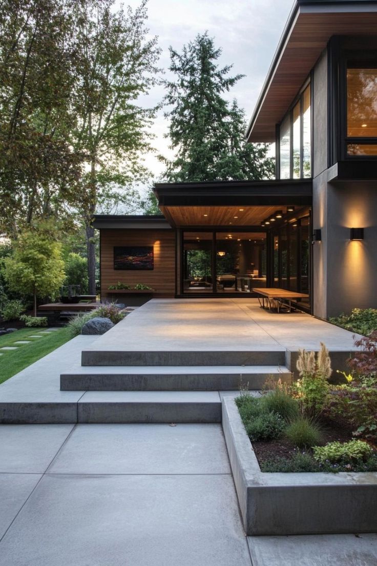 Modern house with concrete steps, patio, and landscaped yard. Wooden accents and large windows.