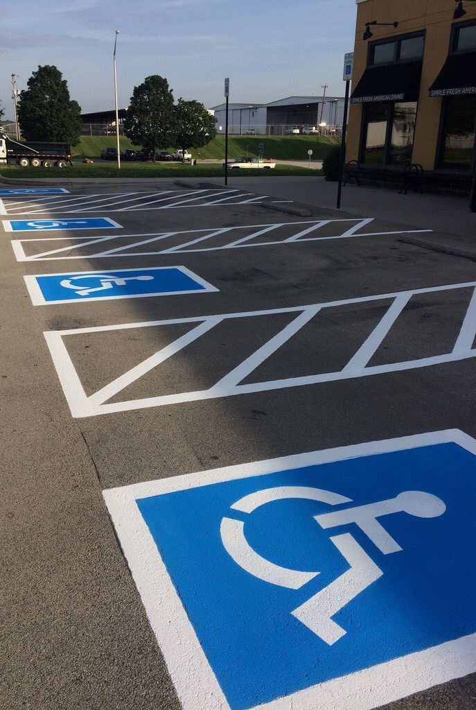 Blue handicapped parking spaces in an asphalt parking lot with white painted markings and the symbol of a person in a wheelchair.