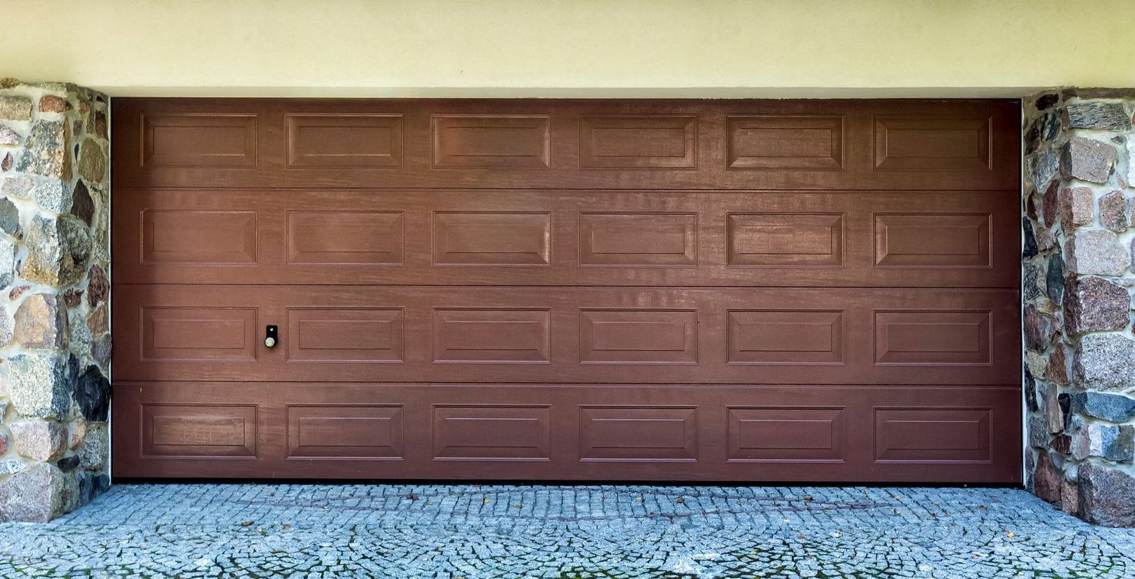 A house with two garage doors and a mailbox in front of it