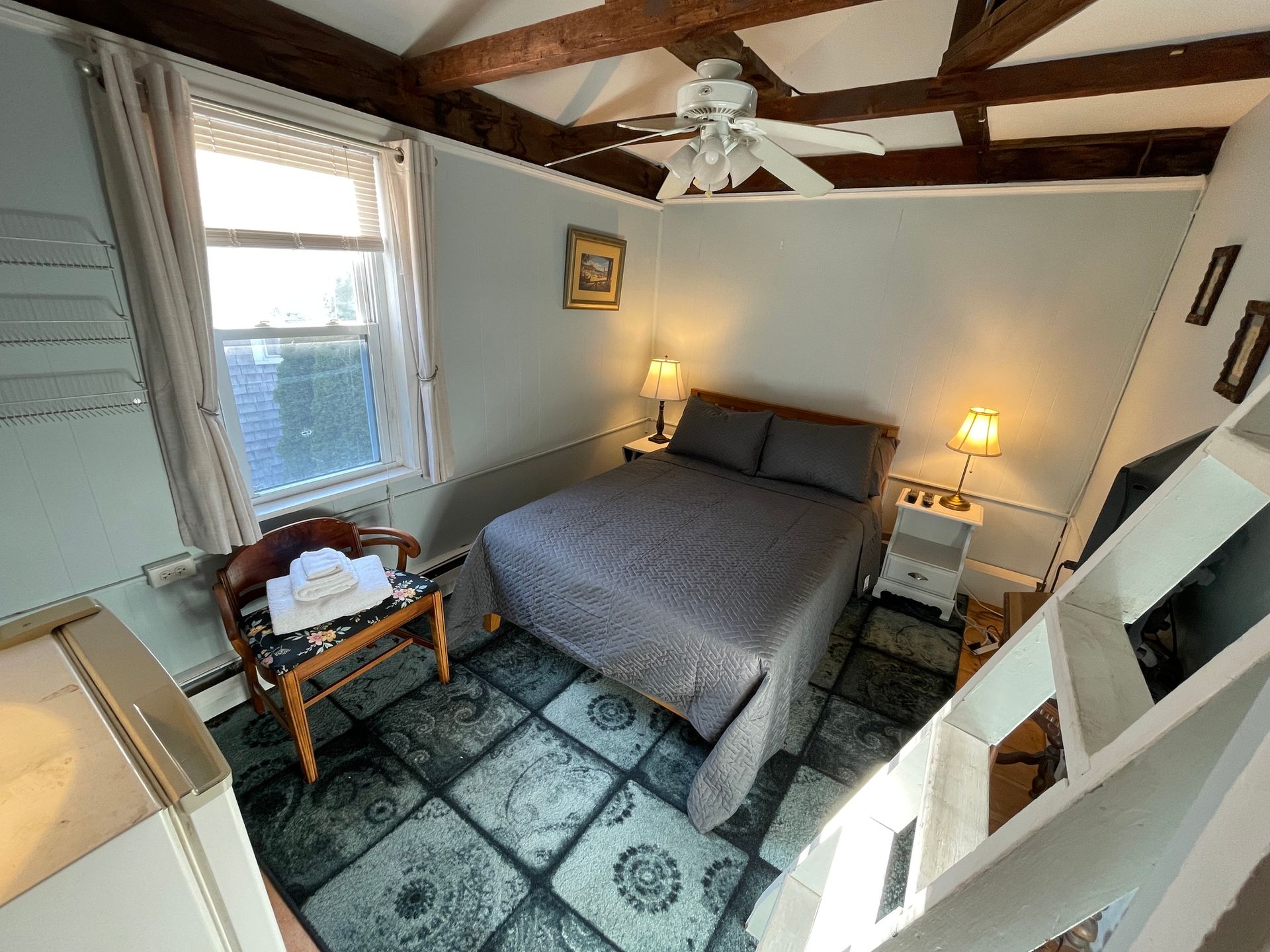 A bedroom with a bed and a ceiling fan