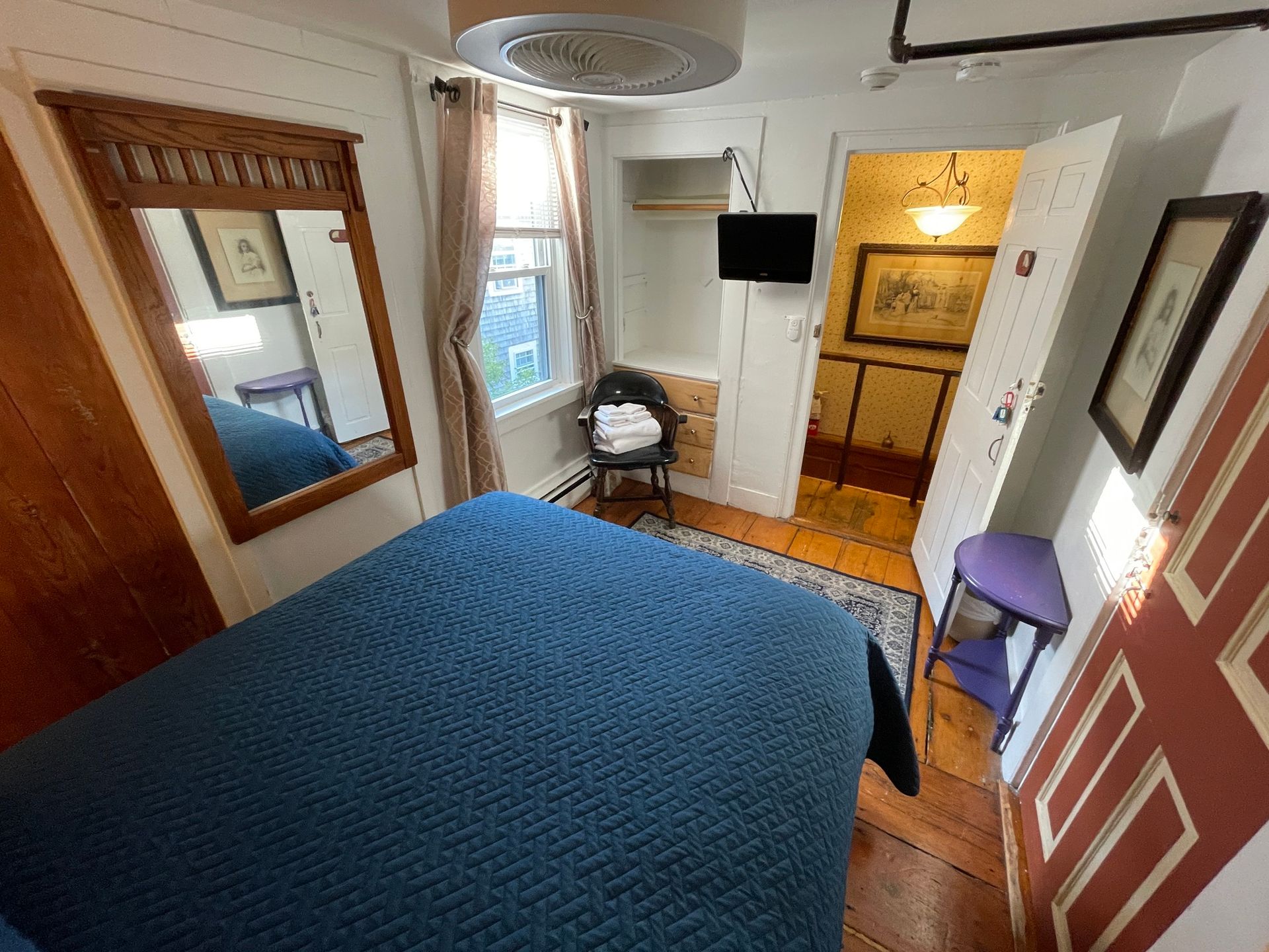 A bedroom with a bed , chair , mirror and television.