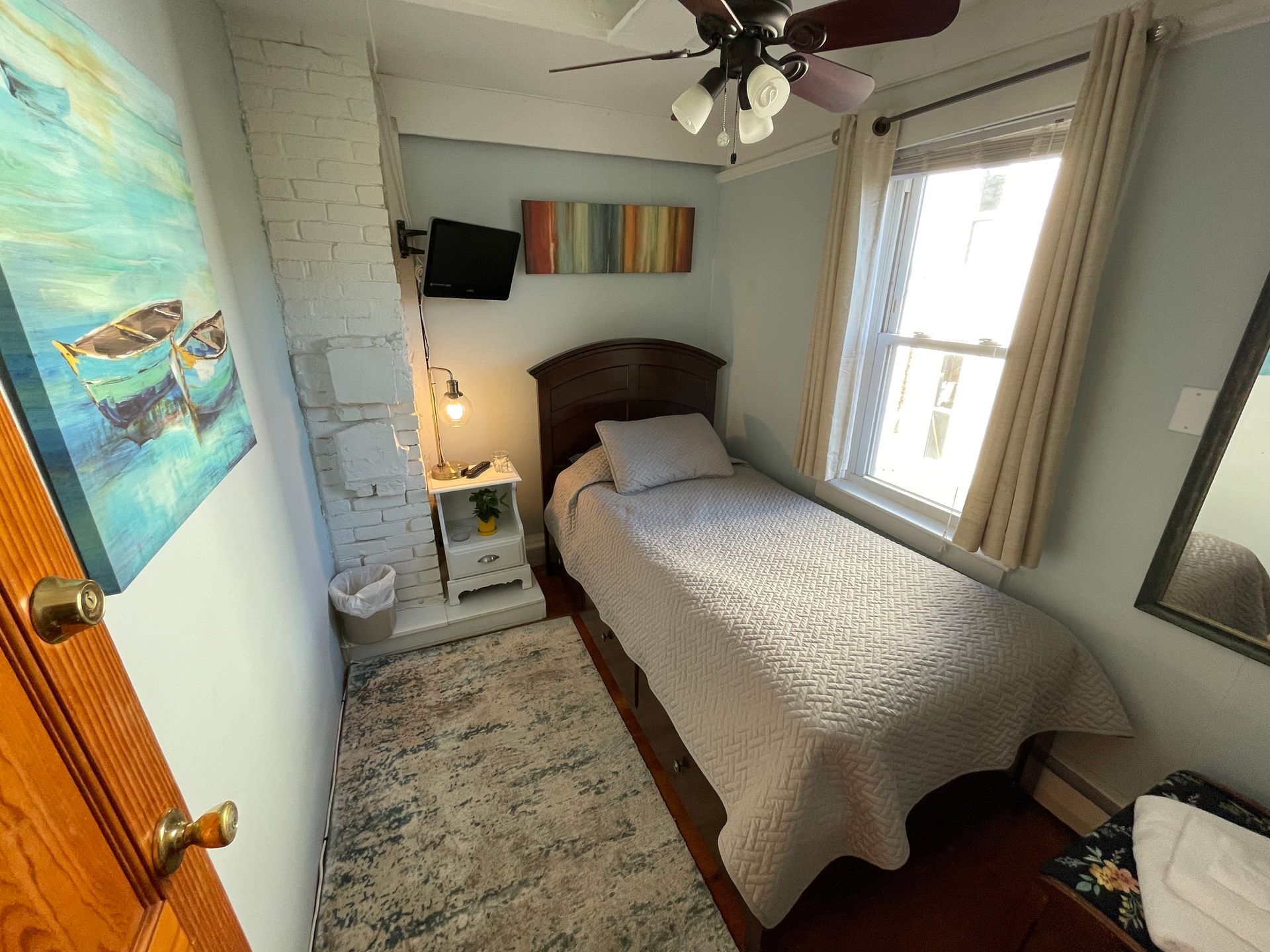 A small bedroom with a single bed and a ceiling fan.