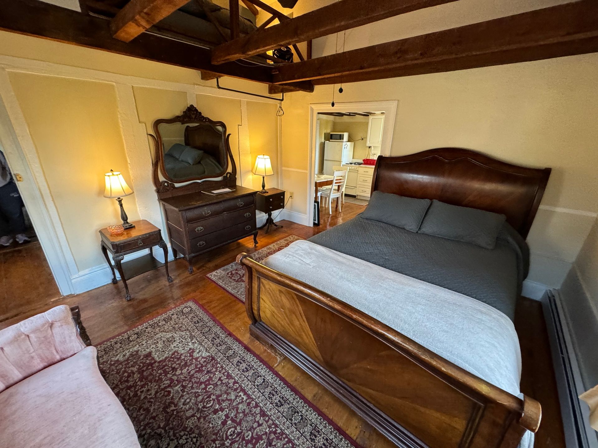 A bedroom with a bed , dresser , mirror and rug.