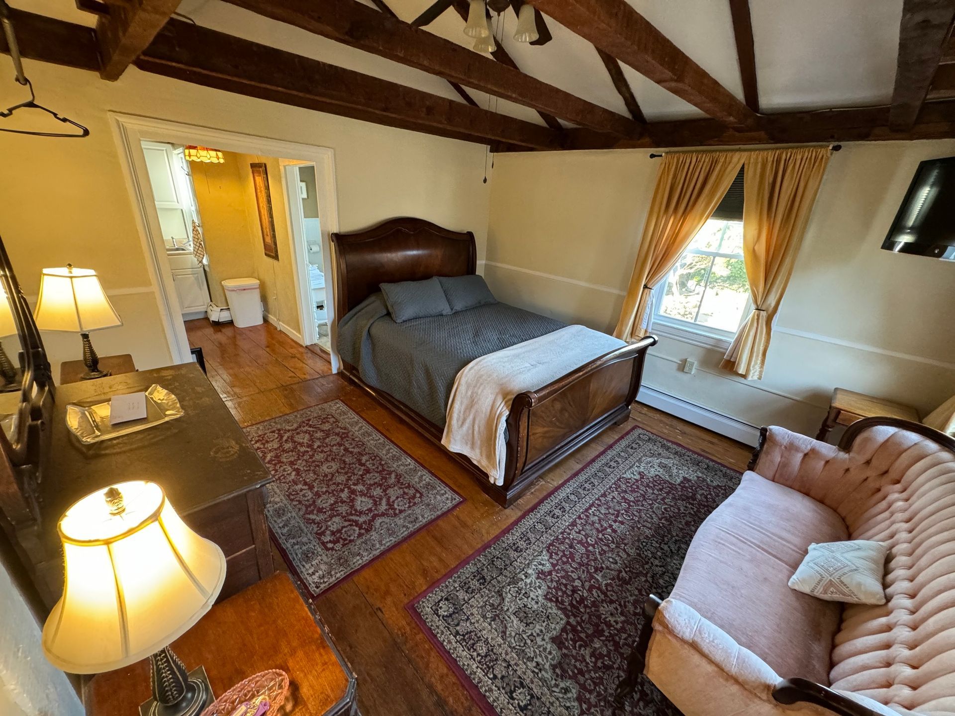 A bedroom with a bed , couch , lamp and rug.