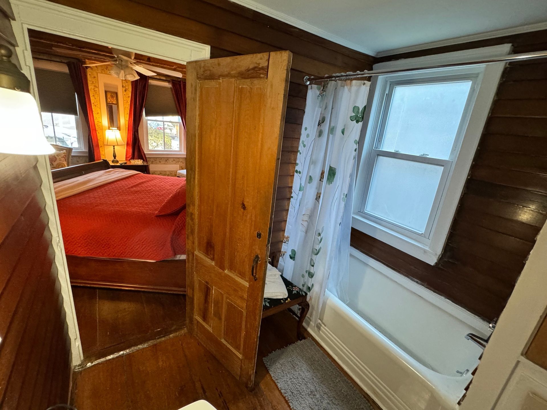A bathroom with a bathtub and a bed in the background.
