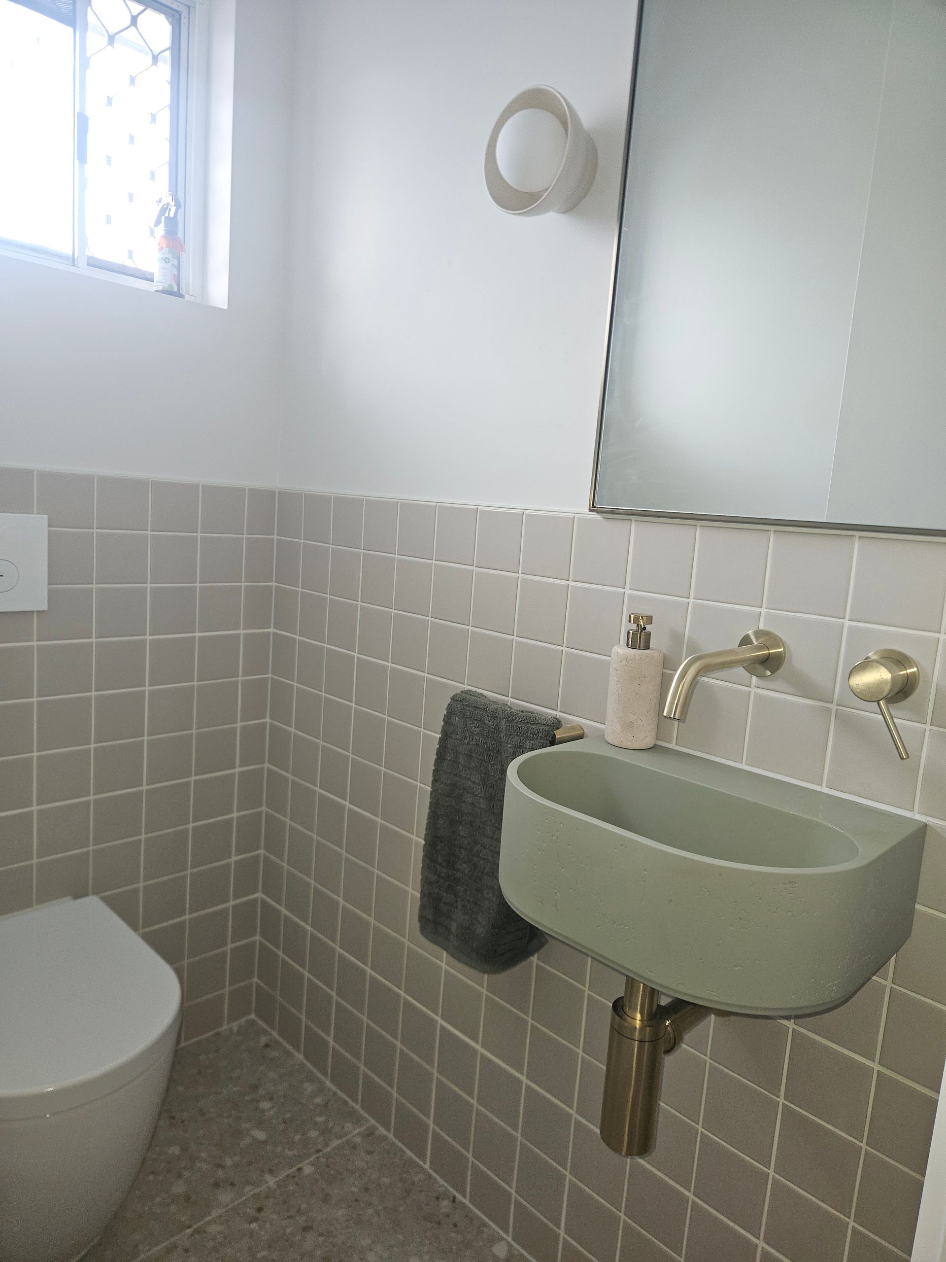 Small bathroom with gray tile, a green sink, and gold fixtures. Toilet is on the left. — Kolora Projects in Robina, QLD