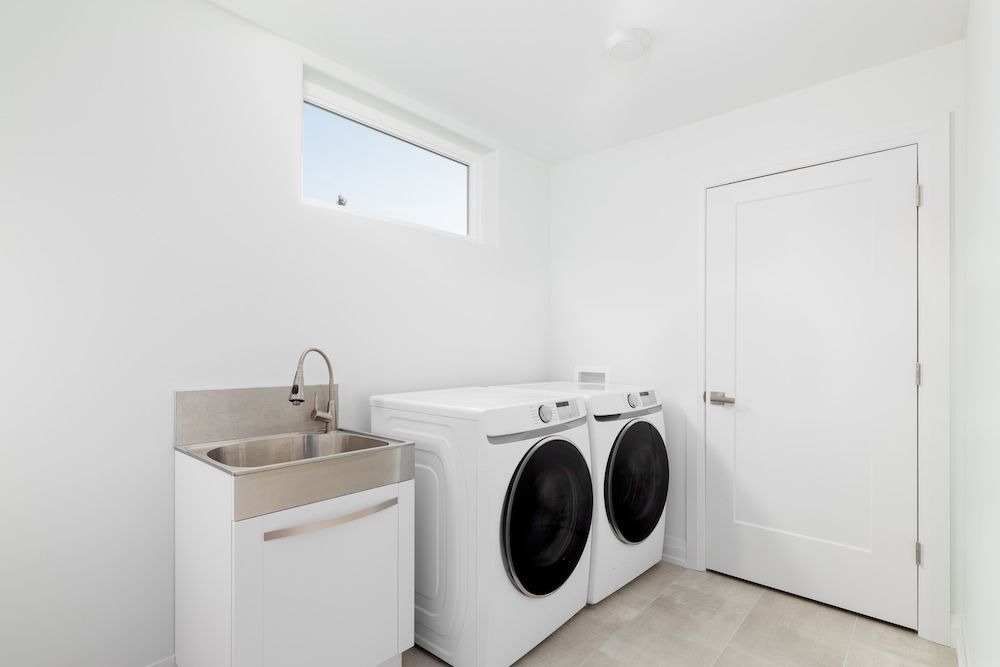 White Laundry Room With Washer, Dryer, Sink, and Closed Door — Kolora Projects in Robina, QLD