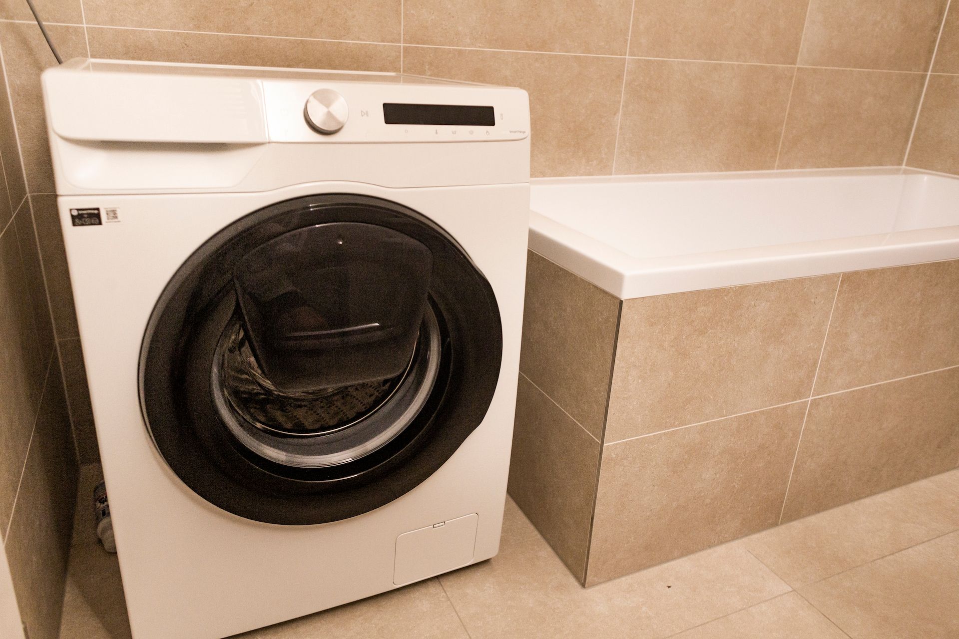 White Washing Machine Next to a Built-in White Bathtub — Kolora Projects in Kingscliff, NSW