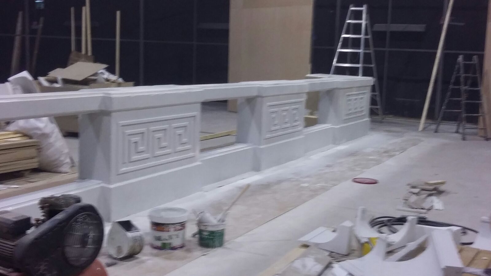 Una habitación con una escalera y cubos de pintura en el suelo.