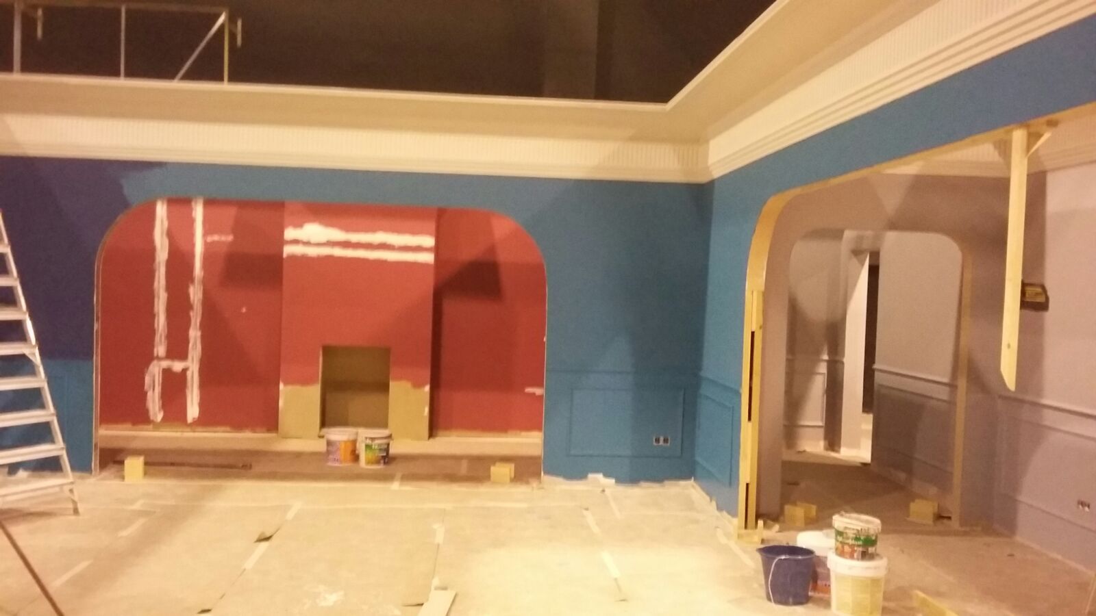 Una habitación con paredes azules y rojas y una escalera.