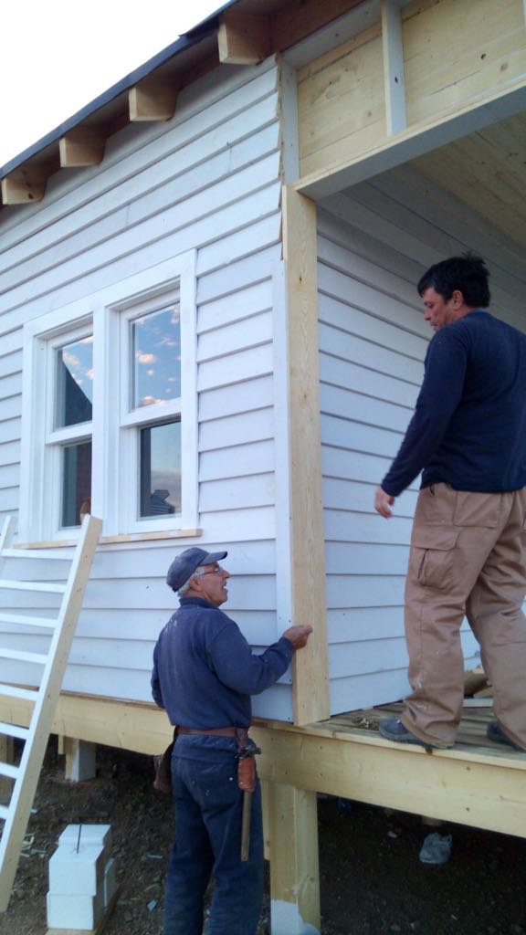 Dos hombres están trabajando en el costado de una casa.