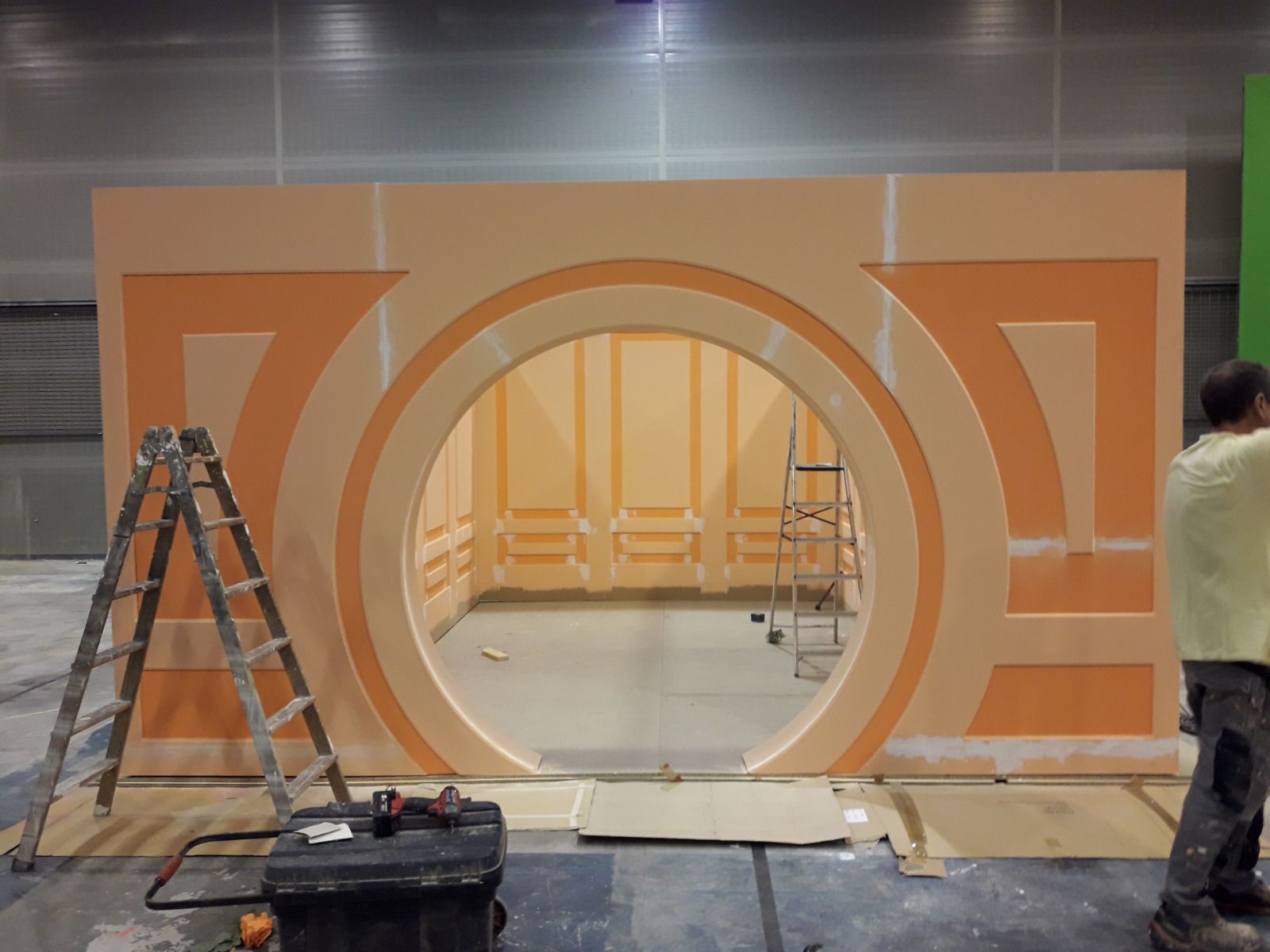 Un hombre está parado frente a una pared con un círculo en el medio.