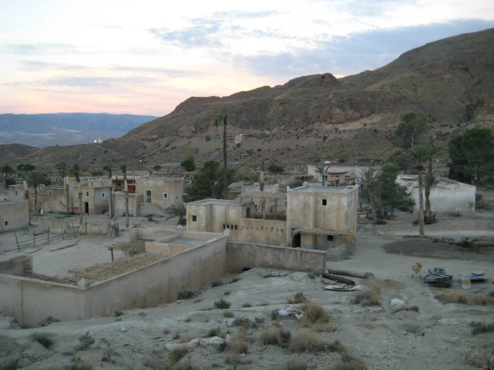 Un pequeño pueblo en el desierto con montañas al fondo.