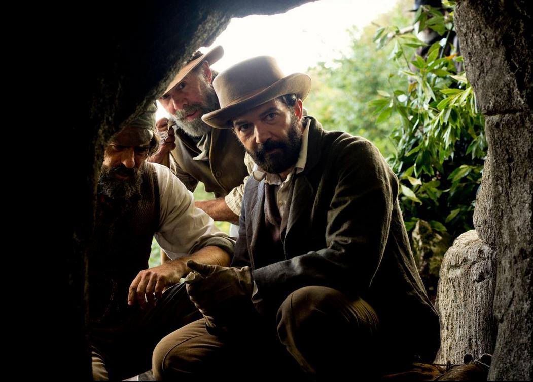 Dos hombres con sombreros miran hacia afuera de una cueva.