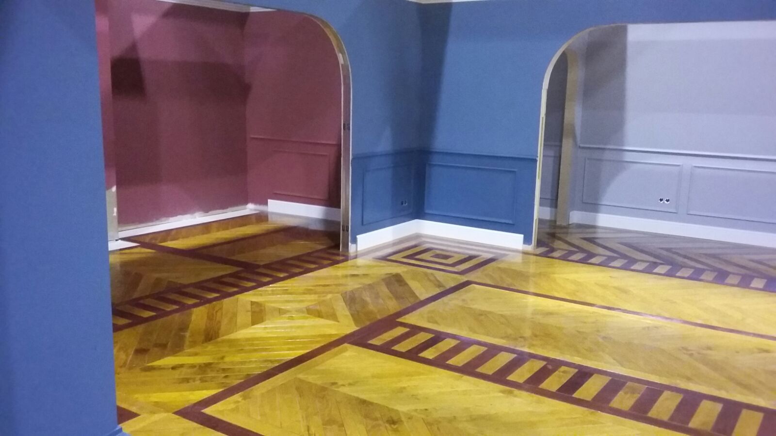 Una habitación con suelo de madera y paredes azules.