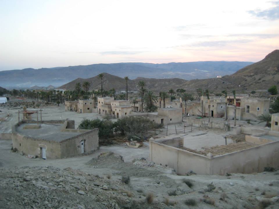 Un pequeño pueblo en el desierto con montañas al fondo.