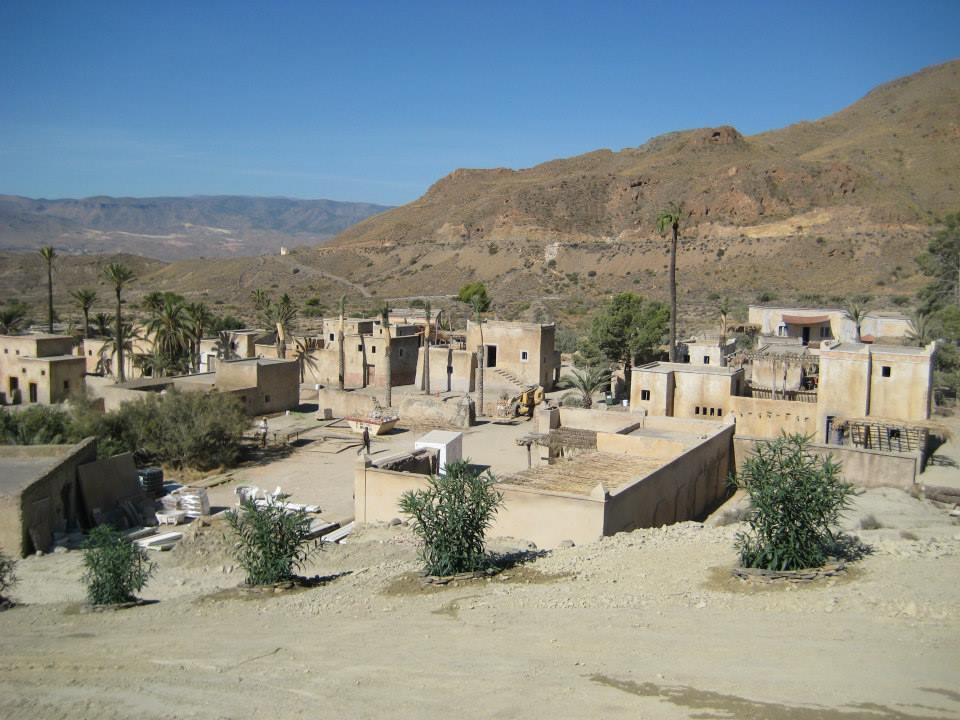 Un pequeño pueblo en el desierto con montañas al fondo.