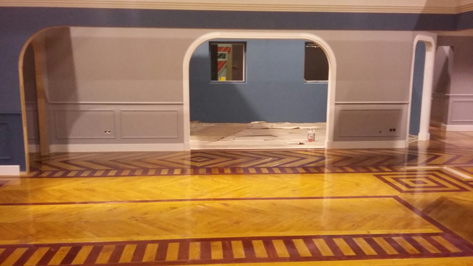 Una habitación con suelo de madera y paredes azules.