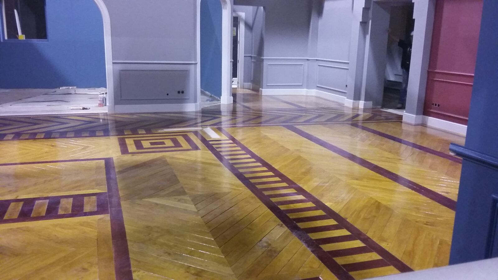 Un pasillo con suelo de madera y un patrón geométrico.