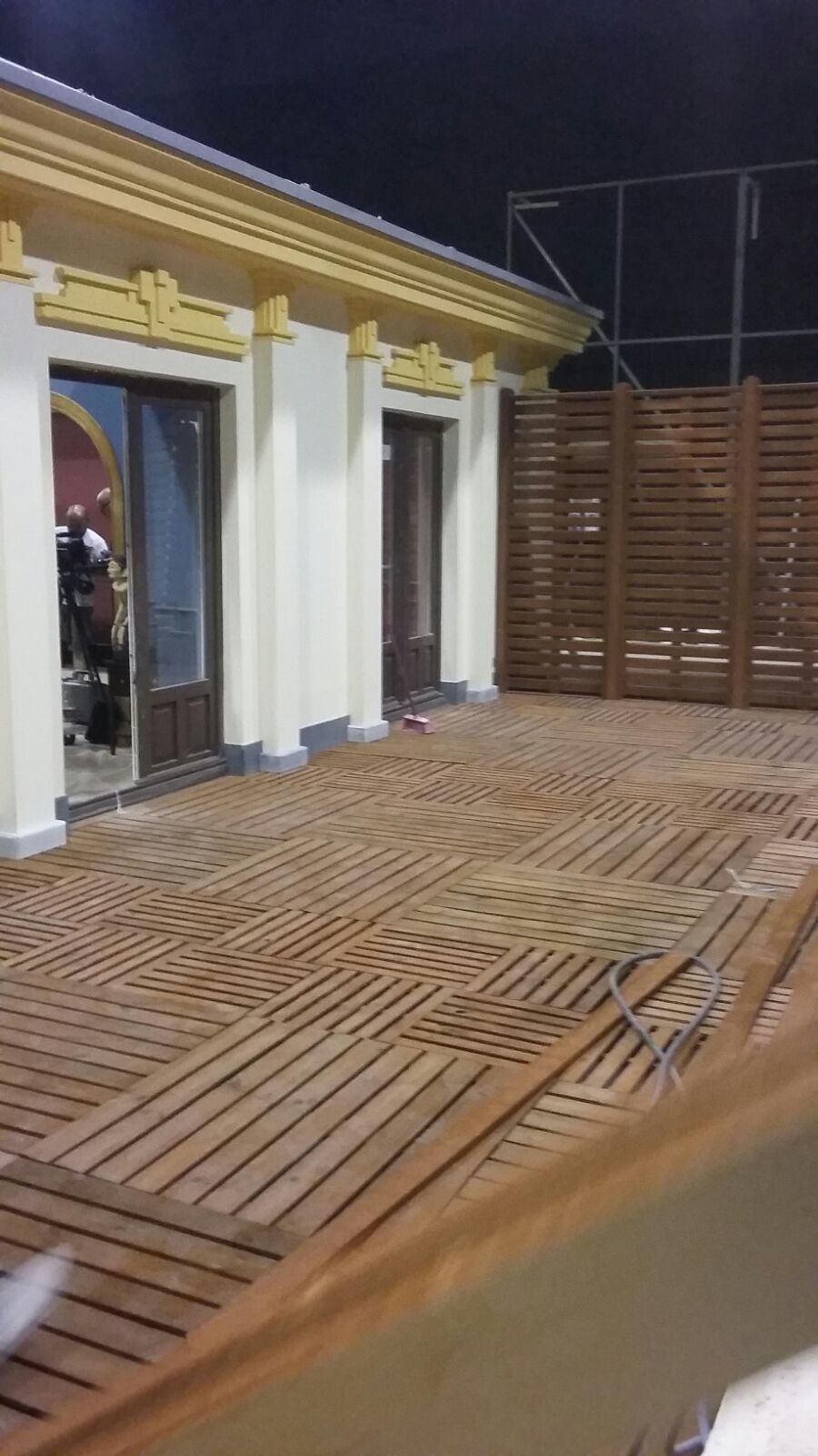 Una terraza de madera frente a un edificio por la noche.