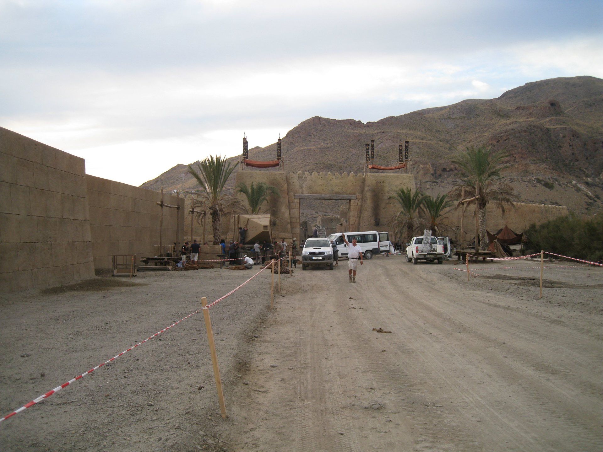 Un camino de tierra que conduce a un edificio con montañas al fondo.