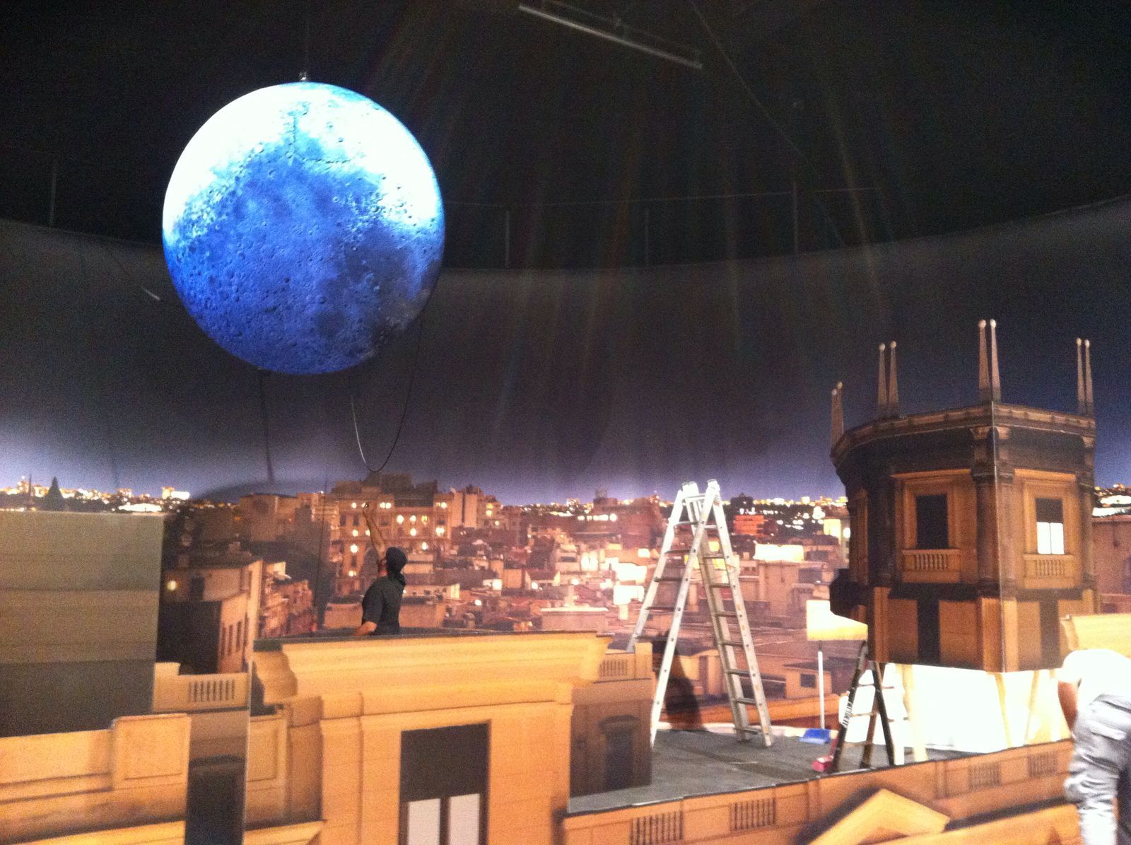 Una gran bola azul cuelga del techo sobre una ciudad.