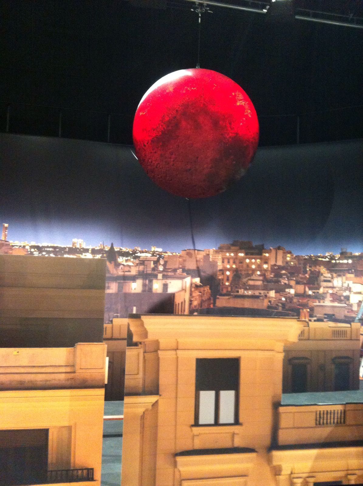 Una gran bola roja cuelga del techo sobre una ciudad.