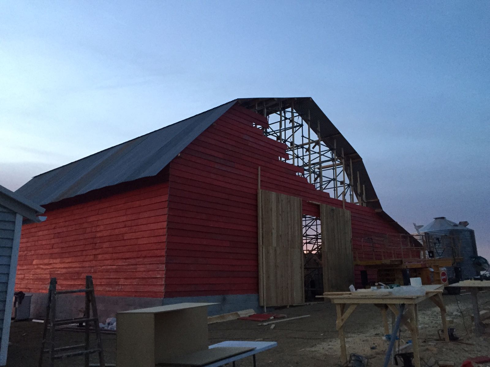 Se está construyendo un granero rojo con techo de metal.