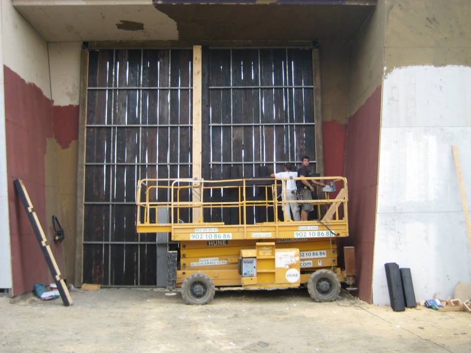 Un elevador de tijera amarillo está estacionado frente a un edificio