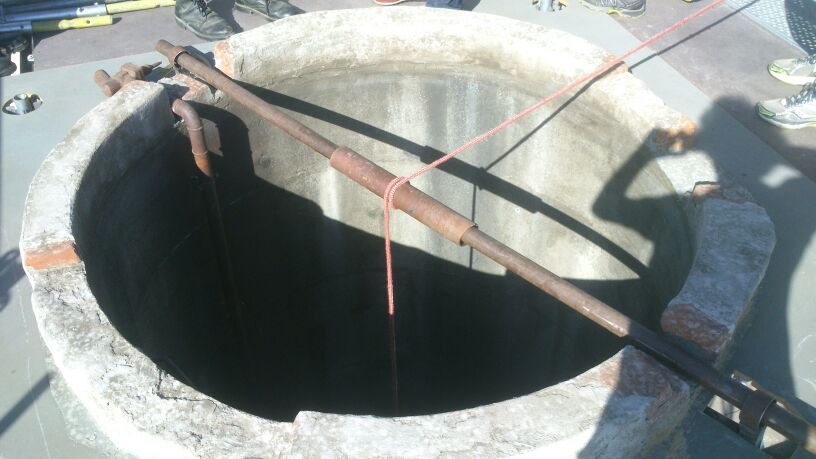 Un gran agujero en el suelo con una cuerda roja atada alrededor.