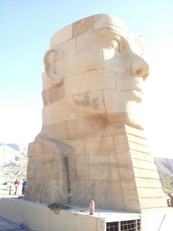 Una gran estatua de la cabeza de un hombre está sentada en la cima de una pirámide.
