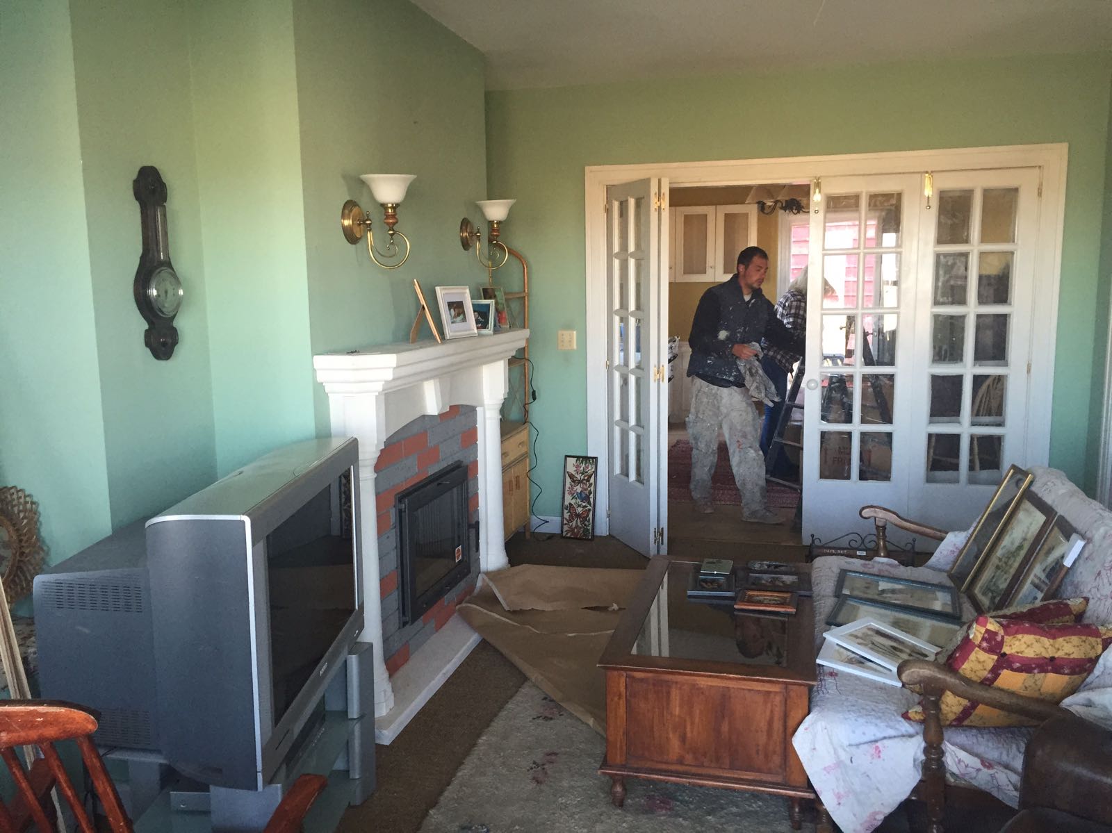 Un hombre está de pie en una sala de estar con un televisor y una chimenea.