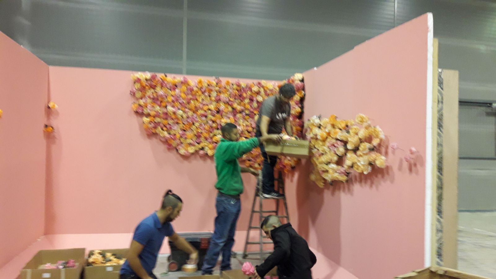 Un grupo de personas está trabajando en una pared rosa.