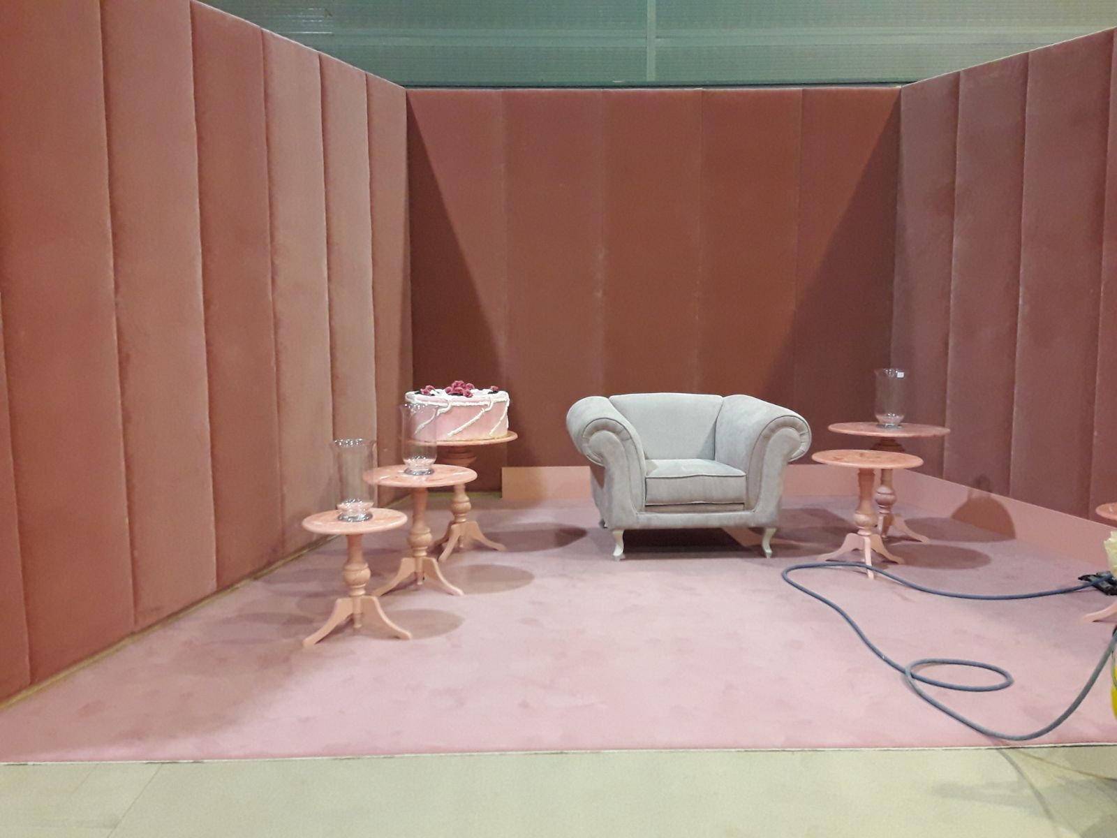 Una habitación con una silla, mesas y un pastel sobre una mesa.