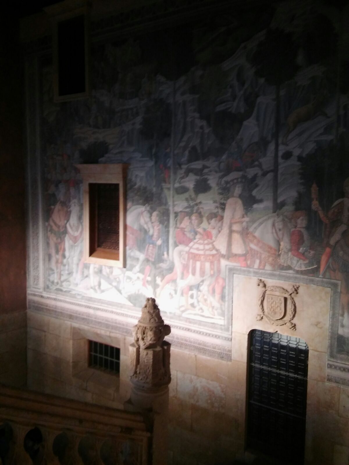 Una pintura en una pared en una habitación oscura con una estatua en primer plano.